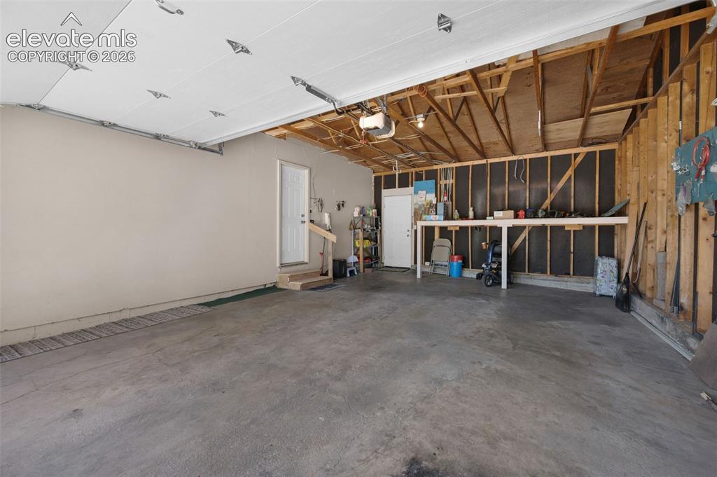 Image 16 of 25: Spacious two-car garage featuring a concrete floor, an overhead garage door