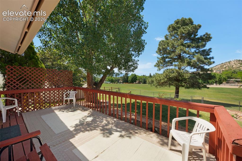 Image 18 of 25: Expansive outdoor deck featuring wood railing and lattice, partially shaded