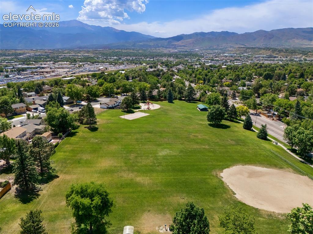 Image 20 of 25: Expansive green space featuring a baseball diamond, playground, and paved w