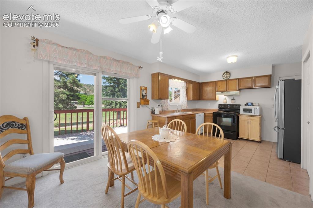 Image 5 of 25: Kitchen with wood cabinetry, black appliances, and neutral-toned countertop