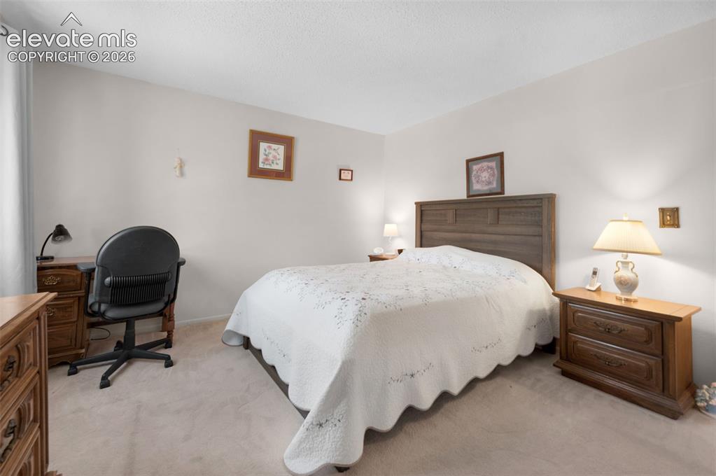 Image 8 of 25: Carpeted bedroom featuring a wooden headboard, light-toned walls, and a win
