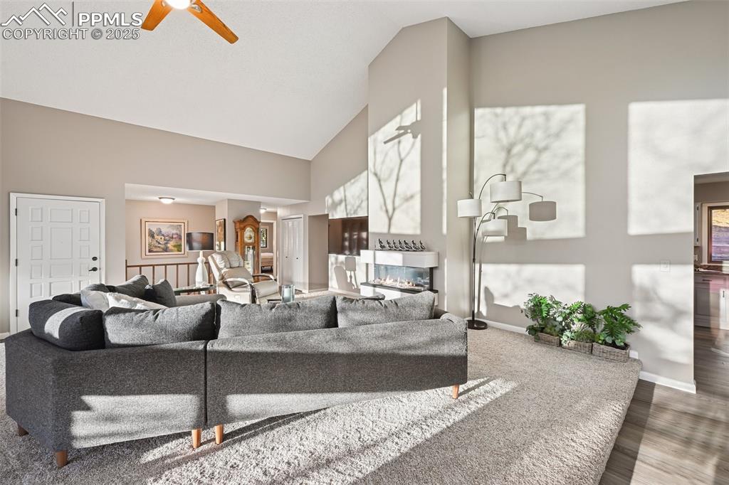 Image 16 of 48: Living area featuring high vaulted ceiling, wood finished floors, a multi s