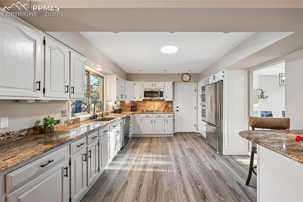 Image 22 of 48: Kitchen with dark stone countertops, tasteful backsplash, light wood-type f