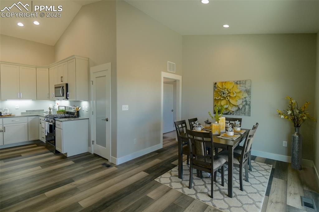 Image 14 of 47: Dining area featuring LTV wood-type flooring and high vaulted ceiling