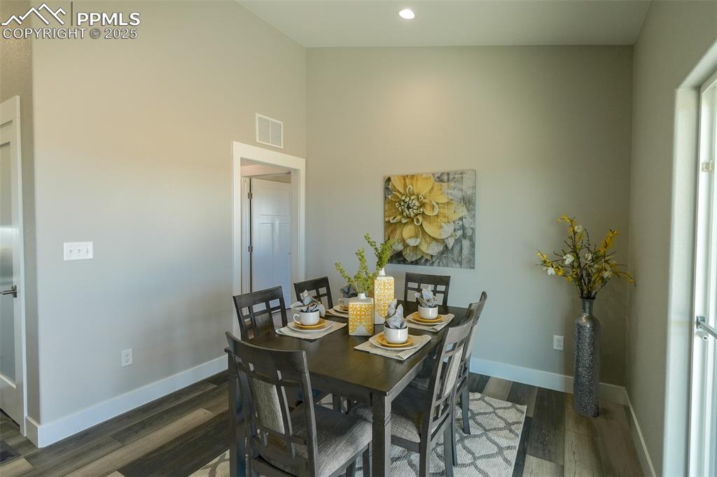 Image 17 of 47: Dining area with dark LTV/ wood-style floors and lofted ceiling