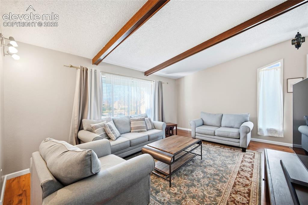 Image 11 of 50: LARGE LIVING ROOM, WOOD BEAMED CEILINGS AND ADJOINS THE FORMAL DINING AREA.