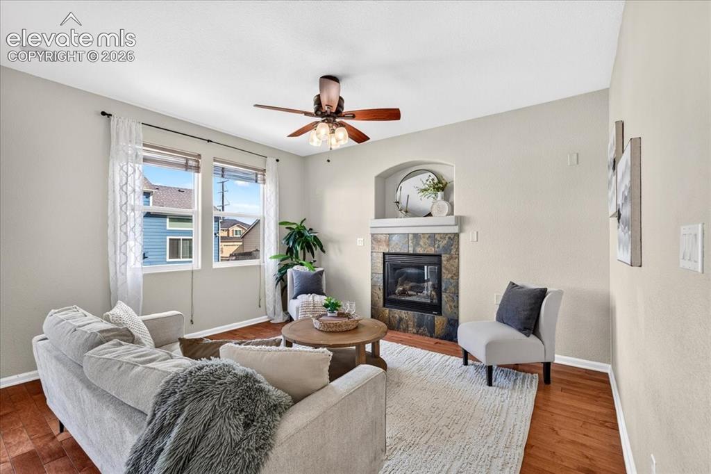 Image 12 of 28: Living space featuring wood-finish flooring, a ceiling fan, and a fireplace