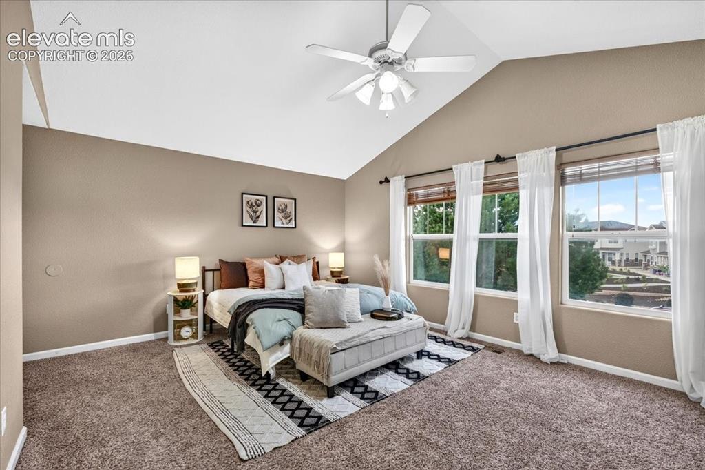 Image 14 of 28: Vaulted ceiling with a ceiling fan, plush carpet flooring, and multiple win
