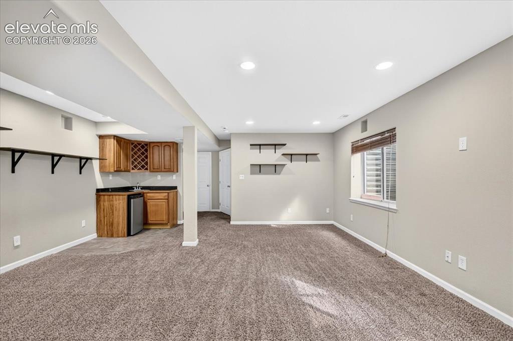 Image 20 of 28: Recessed lighting illuminates the carpeted living area, featuring a built-i