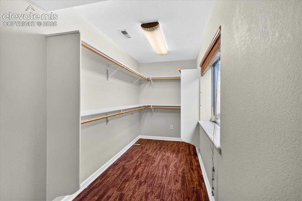 Image 23 of 28: Walk-in closet with wood-finish flooring, built-in shelving, and a window