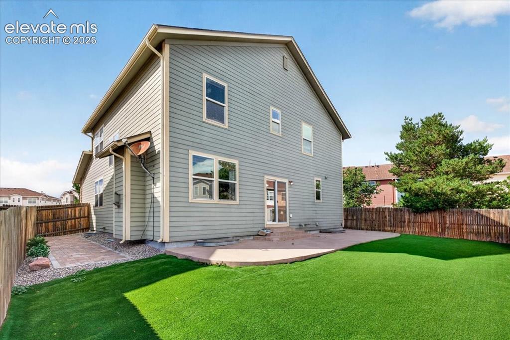 Image 25 of 28: Expansive backyard featuring artificial turf, a concrete patio, and a priva