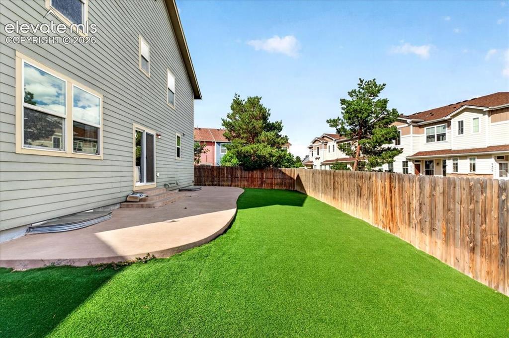 Image 26 of 28: Rear exterior with siding, sliding glass door, curved concrete patio, artif