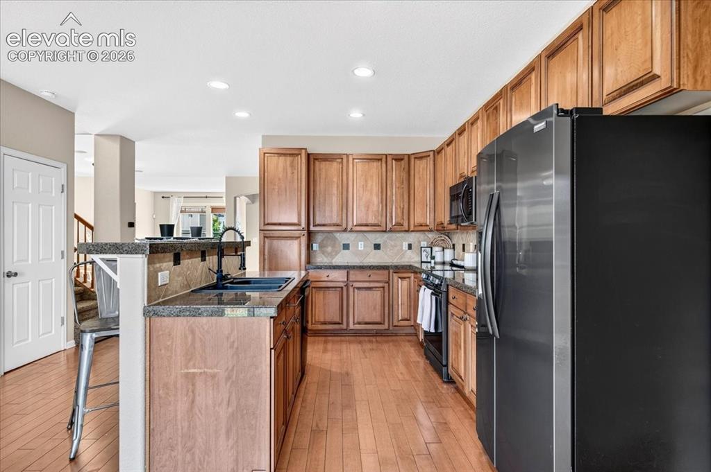 Image 9 of 28: Kitchen featuring wood-finish flooring, wood cabinetry, granite countertops