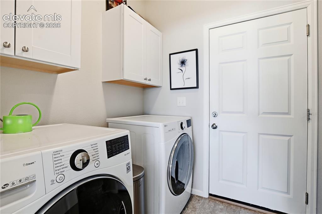 Image 14 of 47: Dedicated laundry area featuring overhead white cabinetry with wood-finish 