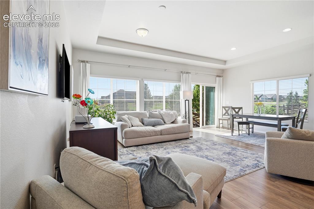 Image 16 of 47: Expansive living area featuring wood-finish flooring, a tray ceiling with r