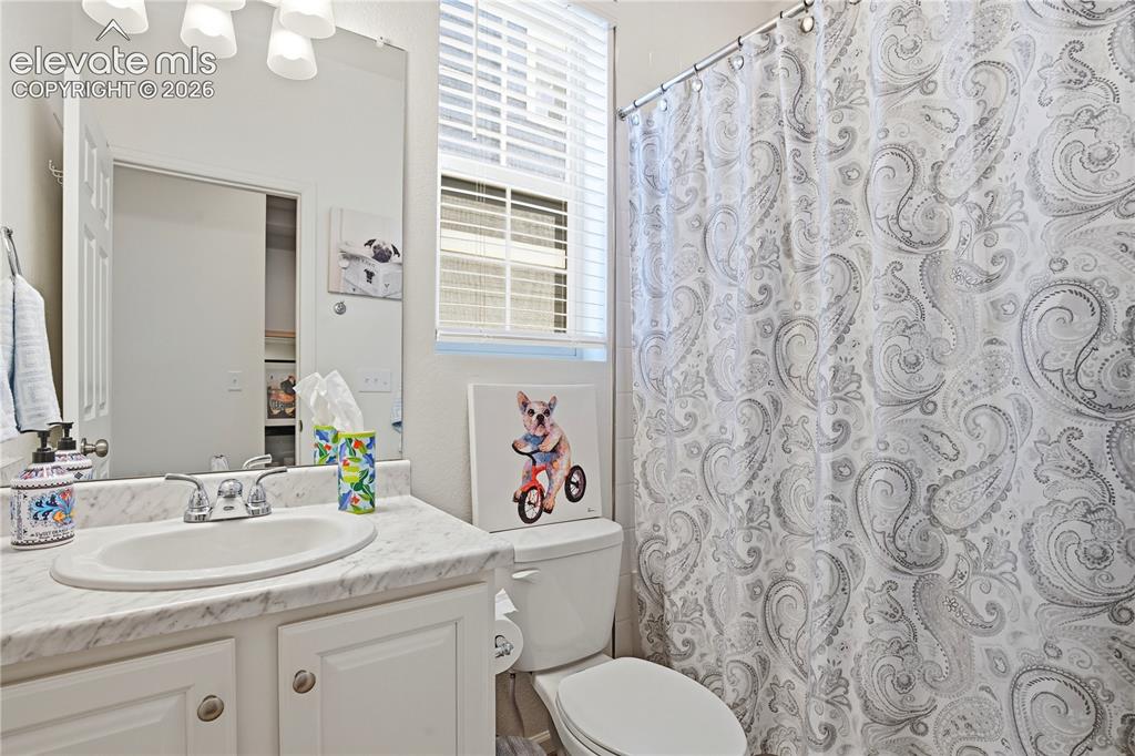 Image 26 of 47: Bathroom featuring a white vanity with an undermount sink, a patterned coun