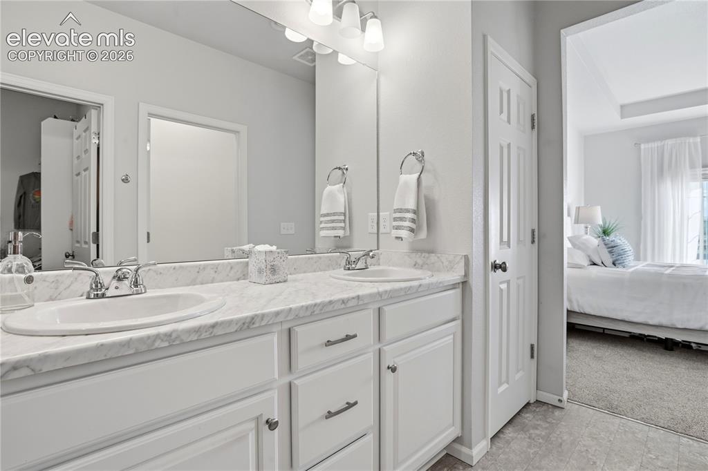 Image 32 of 47: Dual vanity featuring integrated sinks, chrome fixtures, white cabinetry, a