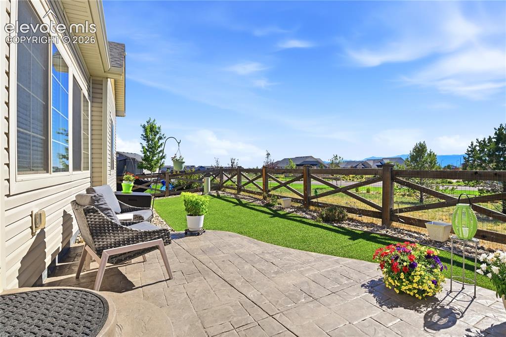 Image 33 of 47: Expansive patio featuring stamped concrete, a manicured lawn, and a wooden 