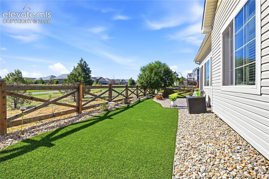 Image 36 of 47: Expansive side yard featuring artificial turf, a decorative wooden fence, a