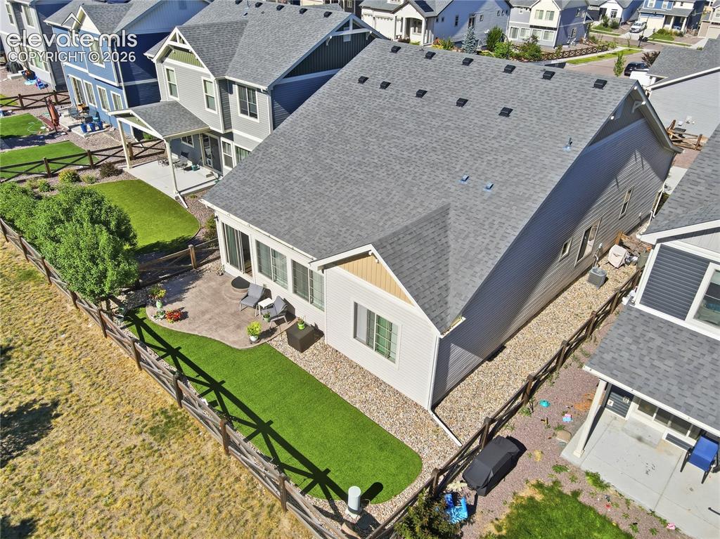 Image 43 of 47: Fenced rear yard featuring a paved patio area, artificial turf, and a matur