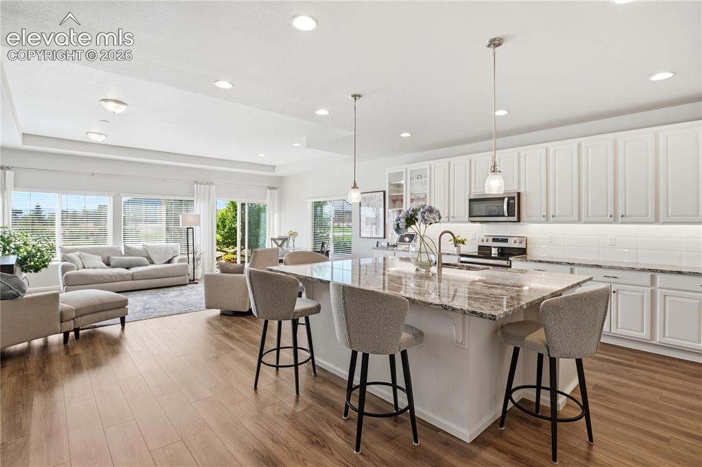 Image 6 of 47: Spacious kitchen featuring a large island with seating, white shaker cabine
