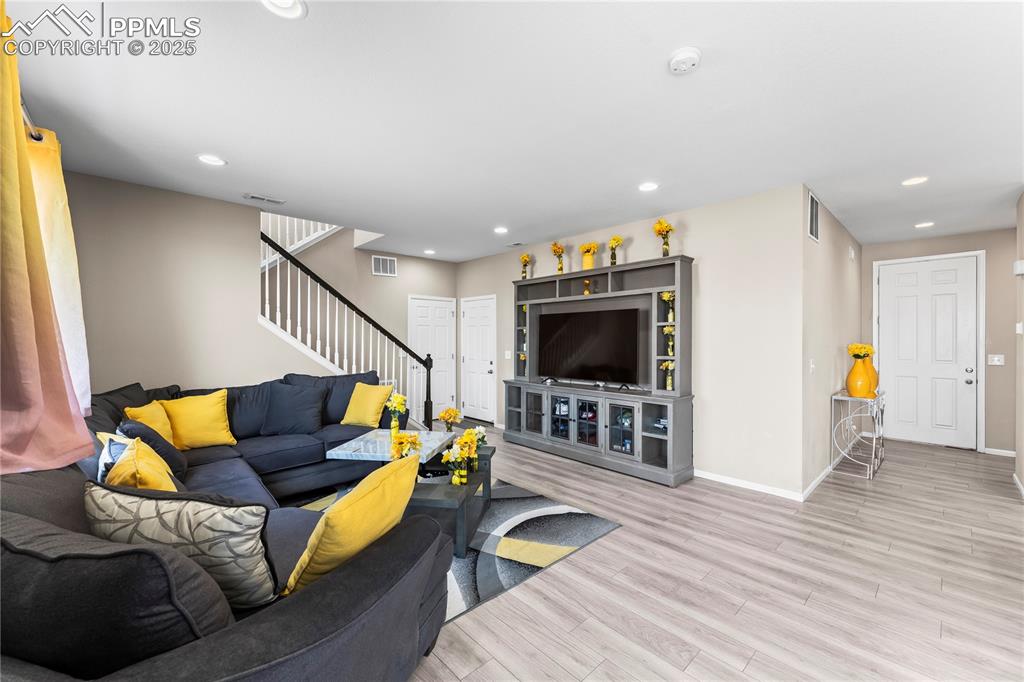 Image 12 of 32: Living area featuring wood finished floors, recessed lighting, and stairs
