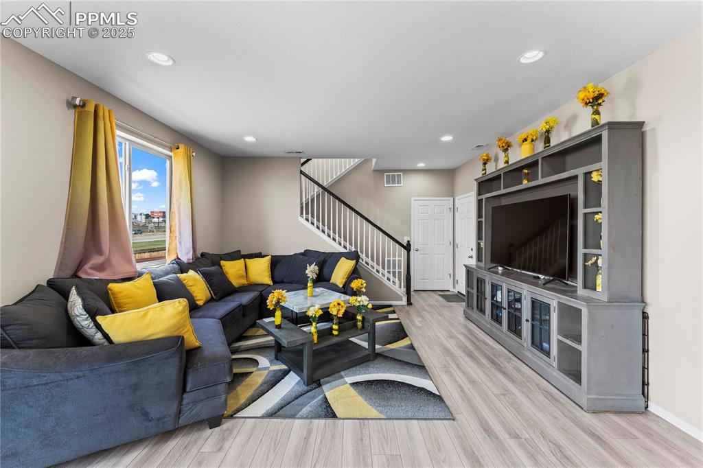 Image 13 of 32: Living area featuring stairs, light wood-style floors, and recessed lightin