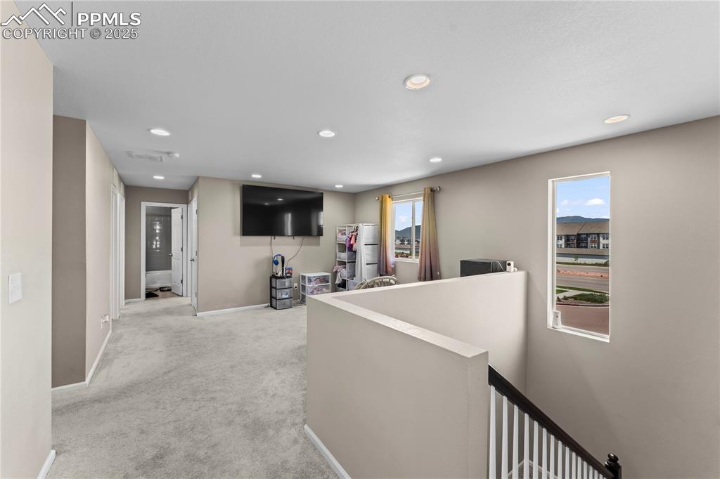 Image 14 of 32: Hallway with an upstairs landing, light carpet, plenty of natural light, an