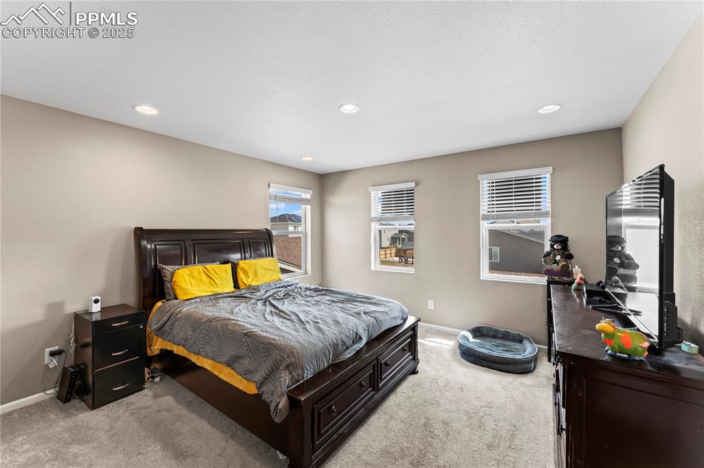Image 17 of 32: Bedroom with light carpet and recessed lighting