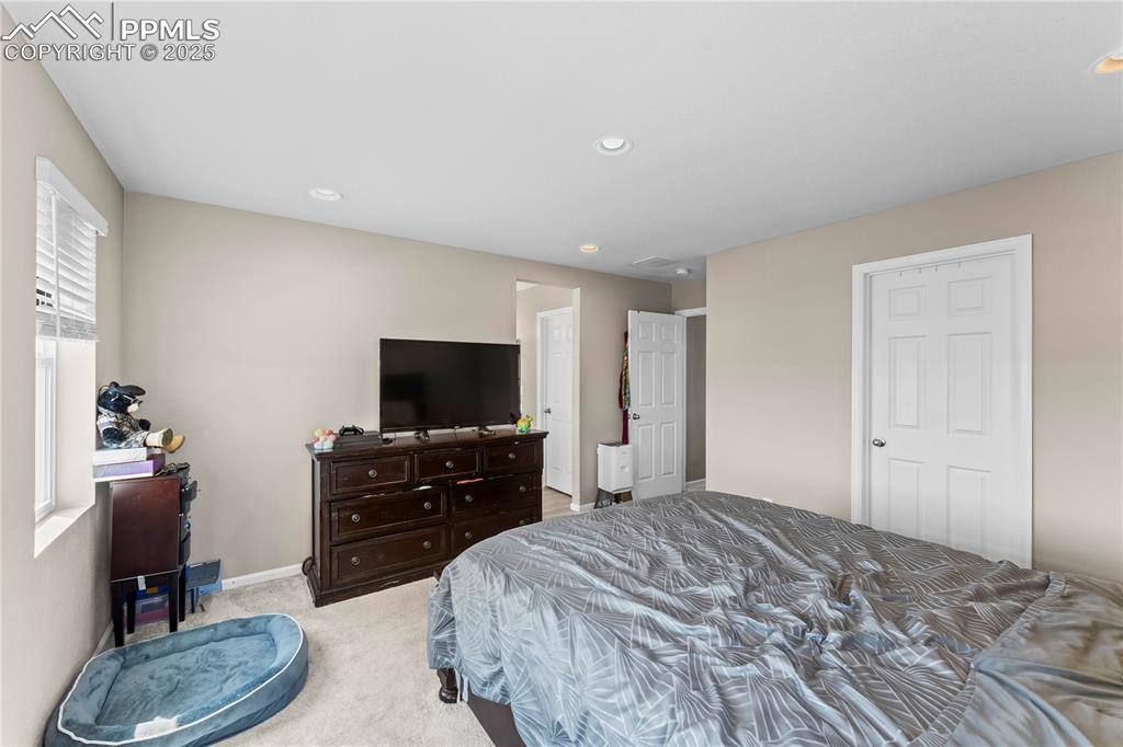 Image 18 of 32: Bedroom with light colored carpet and recessed lighting