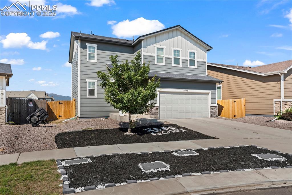Image 2 of 32: Traditional home with board and batten siding, concrete driveway, a garage,