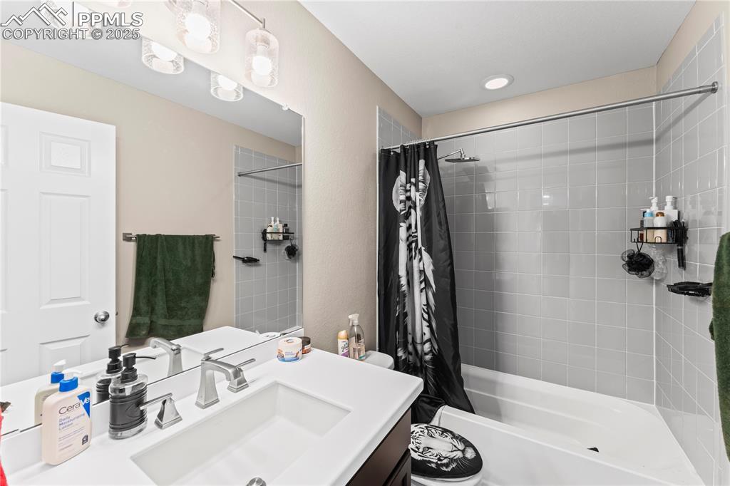 Image 25 of 32: Bathroom with shower / bath combination with curtain and vanity