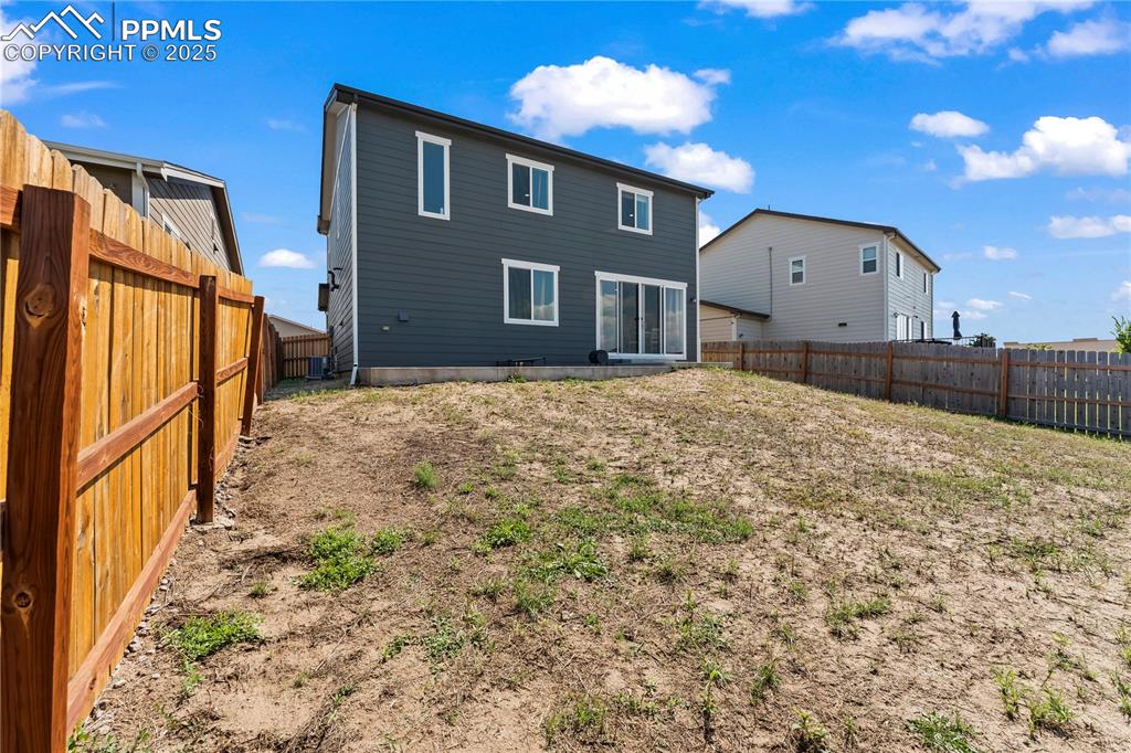 Image 27 of 32: Rear view of house with a fenced backyard