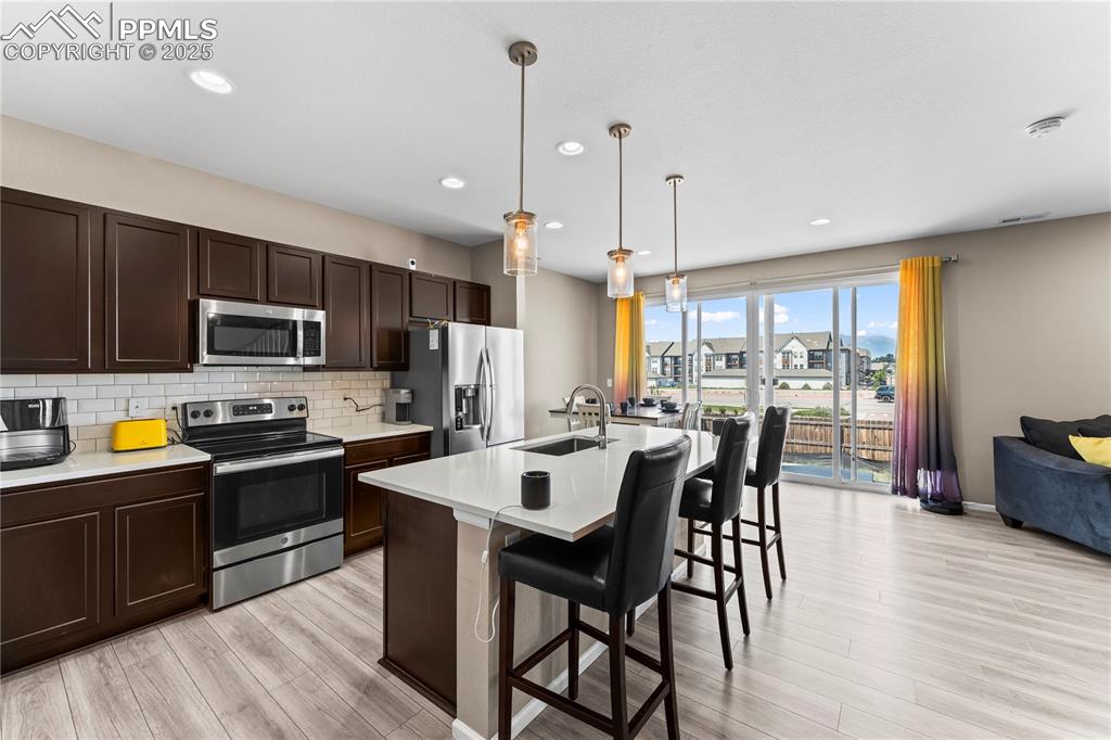 Image 8 of 32: Kitchen featuring stainless steel appliances, dark brown cabinetry, a break