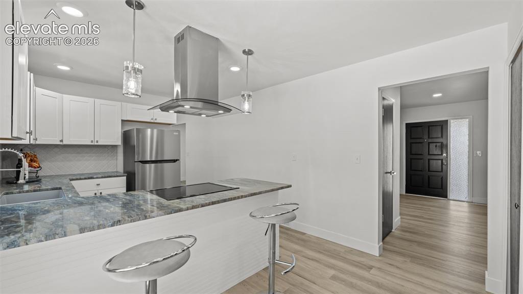 Image 14 of 44: Kitchen featuring white cabinetry, stainless steel appliances, a range hood
