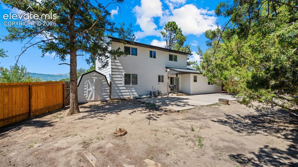 Image 30 of 44: Expansive backyard featuring a privacy fence, mature trees, concrete patio,