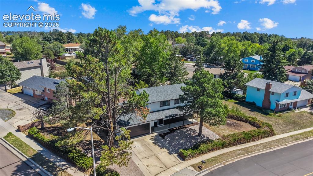 Image 34 of 44: Two-story exterior with a two-car garage, mature landscaping, and an asphal