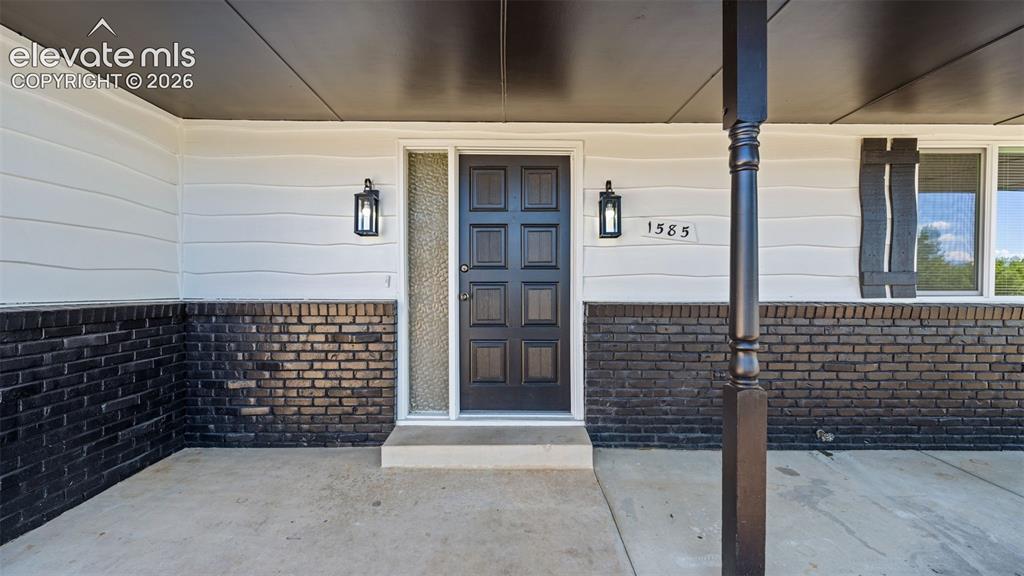 Image 4 of 44: Entryway featuring a paneled door, two exterior sconces, and a side light
