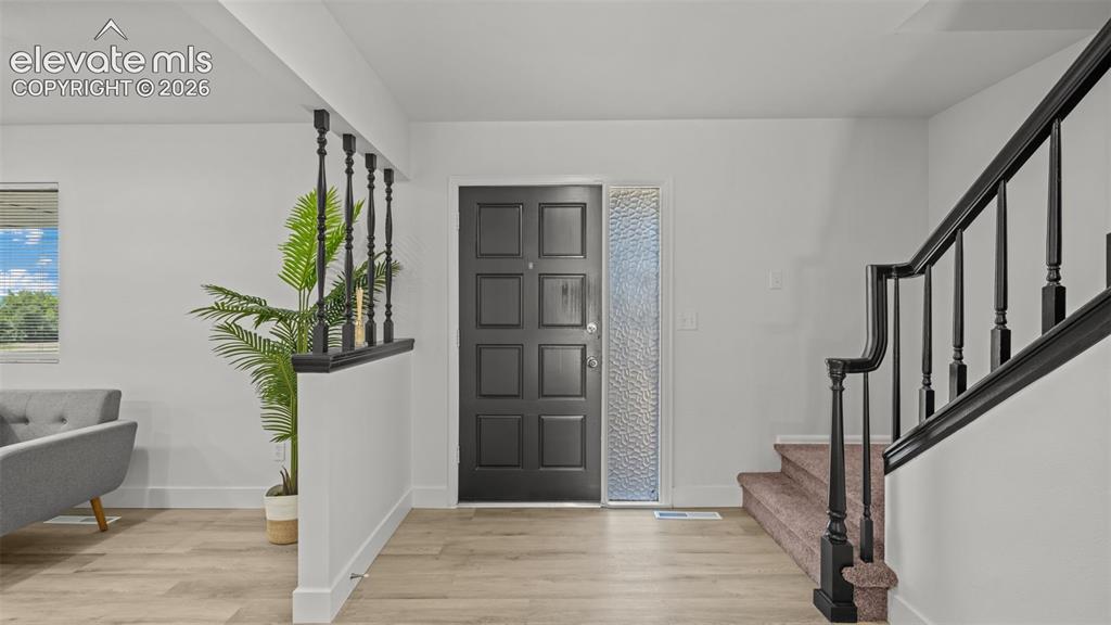 Image 5 of 44: Entryway featuring a paneled door with textured glass sidelight, wood-finis