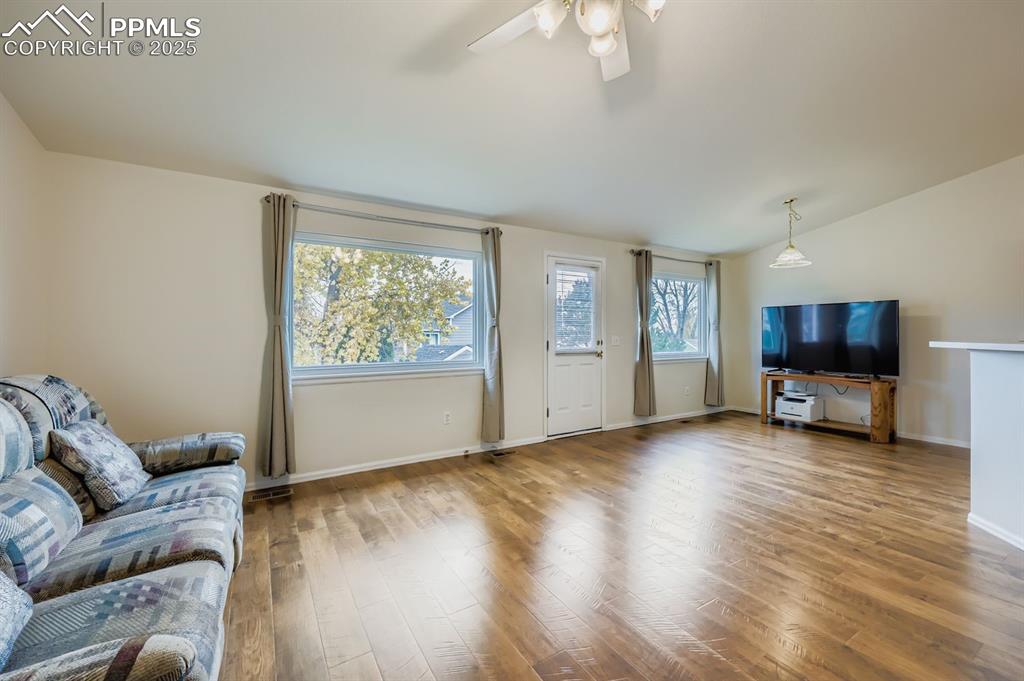 Image 12 of 29: Living area with wood finished floors, a ceiling fan, and lofted ceiling