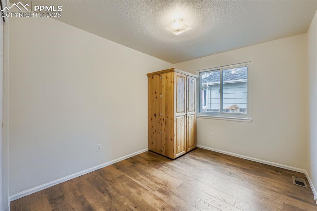 Image 18 of 29: Unfurnished bedroom with hardwood / wood-style flooring and a textured ceil