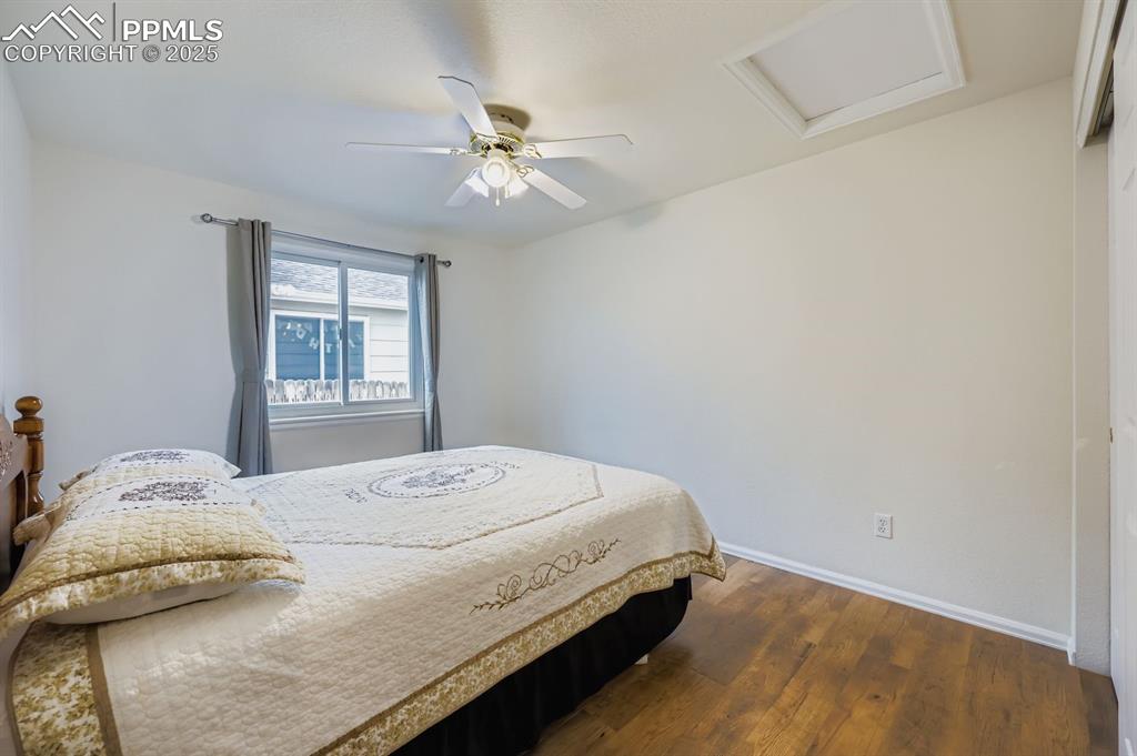 Image 19 of 29: Bedroom featuring attic access, dark wood finished floors, and a ceiling fa