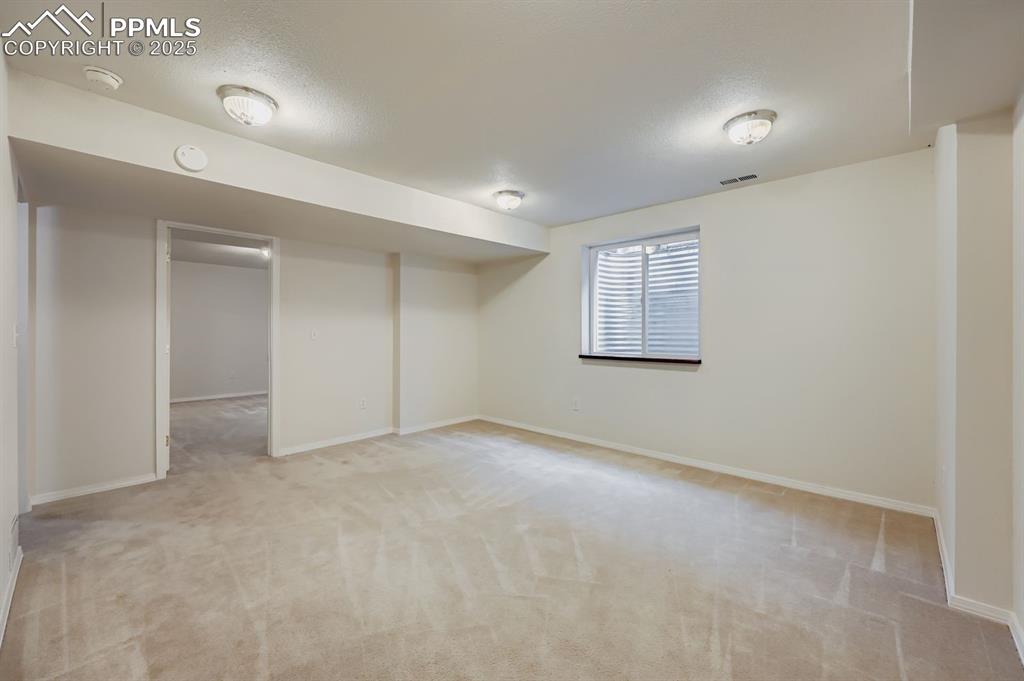 Image 21 of 29: Basement featuring light colored carpet and a textured ceiling