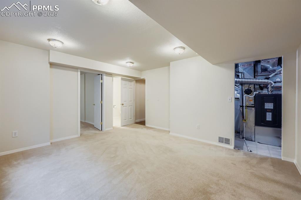 Image 22 of 29: Finished below grade area with light carpet and heating unit