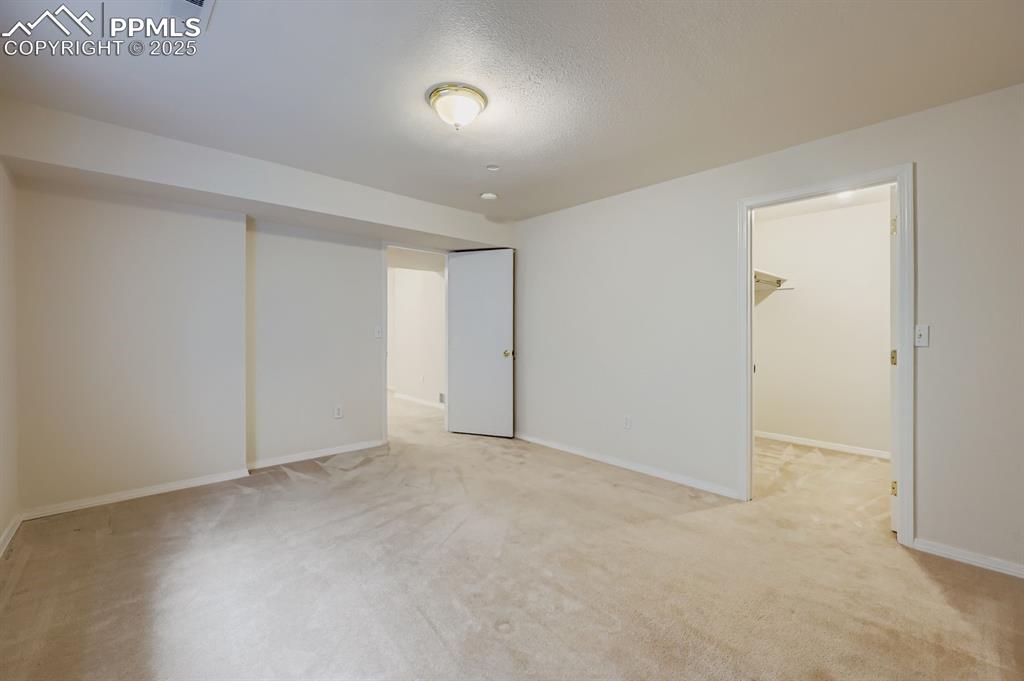 Image 25 of 29: Unfurnished bedroom with a walk in closet, light colored carpet, and a text