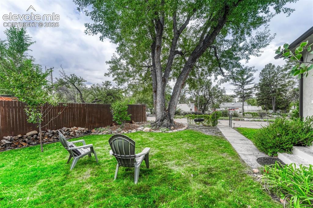 Image 3 of 50: Fully fenced yard with a charming tire swing.
