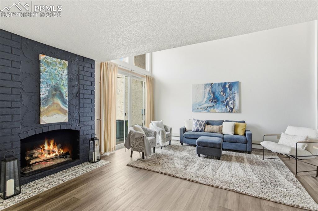 Image 11 of 45: Living room with a brick fireplace, and a wall of windows