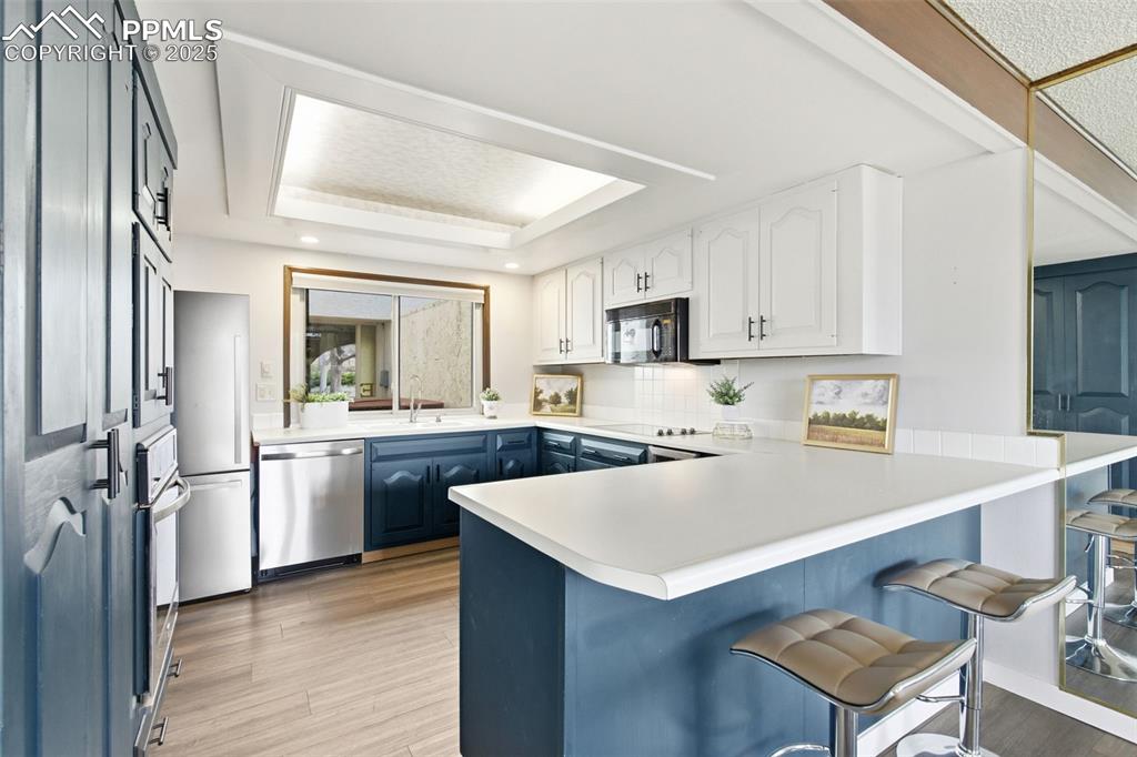 Image 13 of 45: Kitchen featuring blue cabinets, white cabinetry, light countertops, a tray