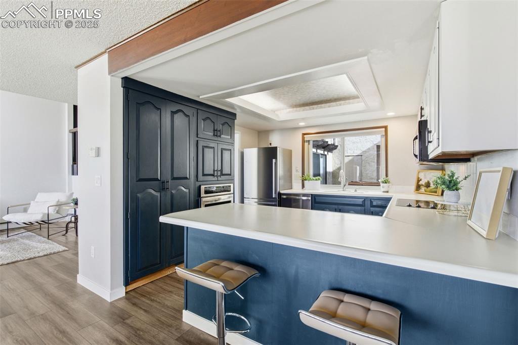 Image 15 of 45: Kitchen with a breakfast bar area, light countertops, appliances with stain