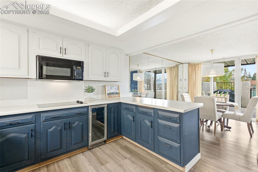 Image 17 of 45: Kitchen featuring a peninsula, light countertops, blue cabinetry, beverage 